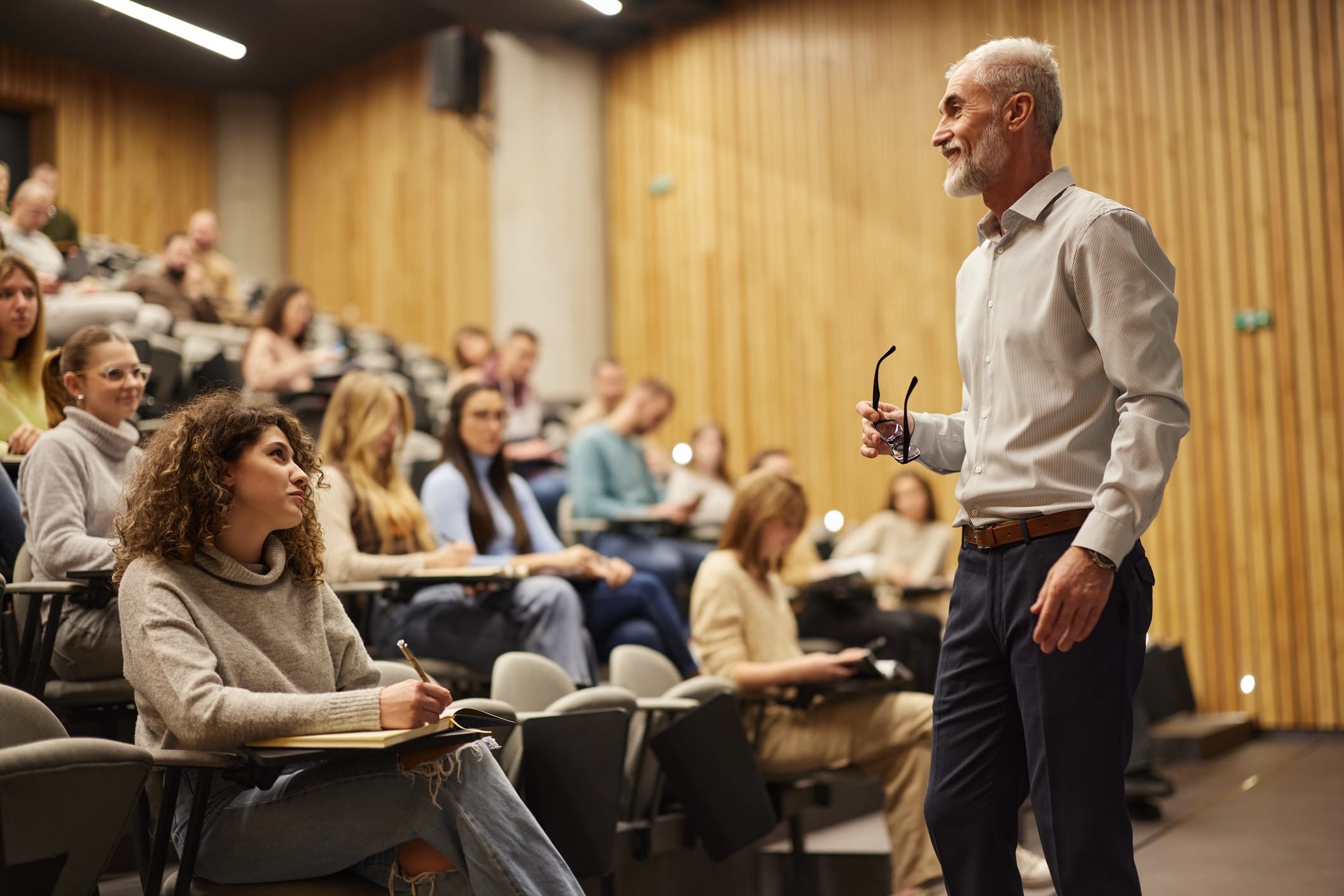 Happy mature professor talking on a class at lecture hall